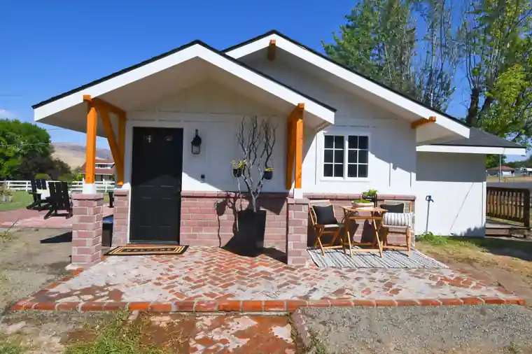 After: the same Selah cottage finished in white with a new porch, cedar posts and a brick patio