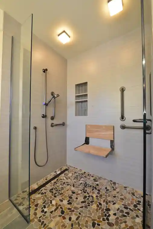 Curbless walk-in shower with a fold-down seat and a grab bar