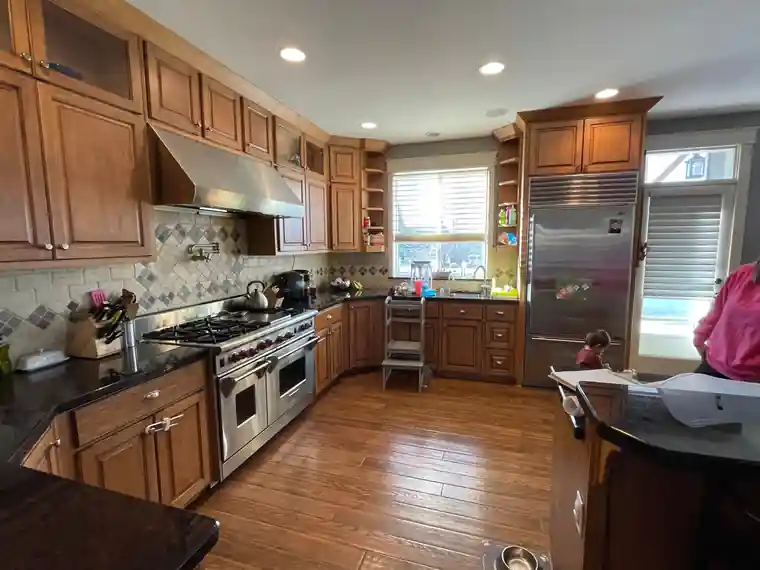 Before: a kitchen with oak cabinets and dated counters, photographed on a phone