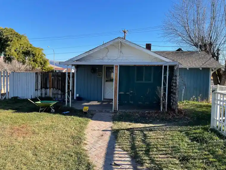 Before: the foreclosed blue cottage in Selah with a sagging porch and overgrown yard