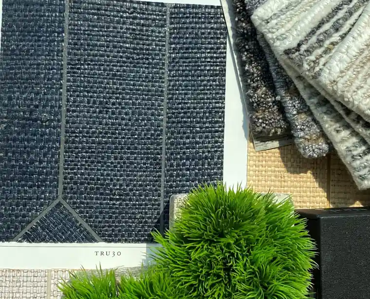 Linen and textured fabric samples beside a potted plant on a design table