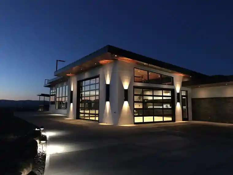 Perry Home exterior at dusk with glass garage doors